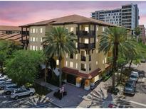 Condo building featuring a tile roof, balconies, and mature palm trees in a sunny setting at 100 4Th S Ave # 220, St Petersburg, FL 33701
