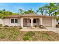 Charming single-story home featuring a well-manicured lawn, arched entryway, and attached single car garage at 13102 Wagner Dr, Hudson, FL 34667