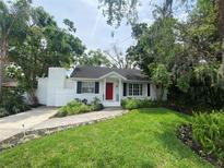 Charming home with a brick walkway, bright red front door and lush landscaping at 3204 W Clinton St, Tampa, FL 33614