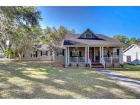 Charming home featuring a welcoming front porch, complemented by a well-manicured lawn and mature trees under a clear, blue sky at 37410 Dixie Ave, Dade City, FL 33525