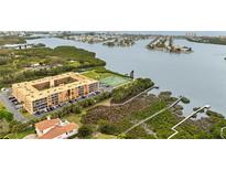 An aerial view of the building, tennis court, dock, and surrounding green landscape with water views at 12760 Indian Rocks Rd # 571, Largo, FL 33774