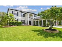 Beautifully landscaped front yard with lush lawn and meticulously maintained hedges complements the home's architecture at 16323 Muirfield Dr, Odessa, FL 33556