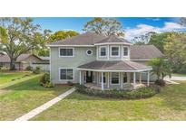 Charming two-story home featuring a cozy, covered front porch and lush landscaping at 22119 Weeks Blvd, Land O Lakes, FL 34639