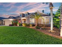 Charming home featuring a well-manicured lawn, beautiful landscaping, and a welcoming facade under a colorful evening sky at 22932 Collridge Dr, Land O Lakes, FL 34639