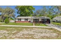 Charming single-story home featuring a well-manicured lawn, brick accents, and a covered carport at 39233 9Th Ave, Zephyrhills, FL 33542