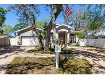 Charming single-story home featuring a brick driveway, mature trees, and an American flag at 5001 44Th N Ave, St Petersburg, FL 33709