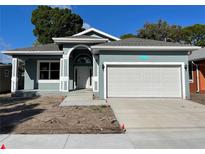 Newly constructed single-Gathering home with an attached two-car garage, and well manicured lawn on a sunny day at 5710 42Nd N St, St Petersburg, FL 33714
