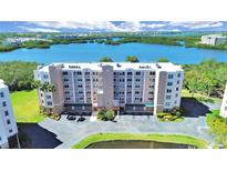Aerial view of a seven-story condo building surrounded by lush landscaping and a serene waterfront at 6495 Shoreline Dr # 8105, Seminole, FL 33708