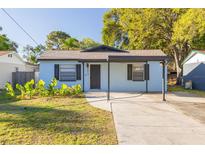 Charming single-story home featuring a covered front porch, blue siding, and mature trees at 6672 56Th N Ave, St Petersburg, FL 33709