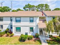 Charming two-story condo building with well-maintained landscaping, colorful flowers, and stairs to the unit entrance at 106 Meadow Ln # 106, Oldsmar, FL 34677