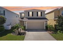 Two-story home with a large garage, well-kept lawn, and decorative landscaping enhancing its curb appeal at 11301 Hudson Hills Ln, Riverview, FL 33579