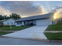 Charming single-story home with a well-maintained lawn and a large driveway leading to an attached two-car garage at 1660 Caledonia Dr, Palm Harbor, FL 34684