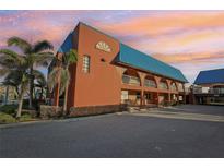 Charming building featuring unique architectural details, a blue roof, and a spacious parking area at 17035 Gulf Blvd # 202, North Redington Beach, FL 33708