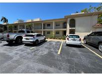 Apartment building featuring a parking lot with multiple parked vehicles on a sunny day at 19029 Us Highway 19 N # 2-12, Clearwater, FL 33764