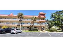 Condo building exterior with palm trees, a unique architectural style, and parking spaces at 2402 Ecuadorian Way # 20, Clearwater, FL 33763