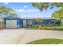 Charming blue home with a well-maintained front yard, long driveway, and a one-car garage under a blue sky at 2866 54Th N St, St Petersburg, FL 33701