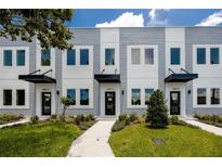 Modern townhome exterior with manicured lawn, tidy shrubs, gray and white facade, and black awning detail at 3402 E 28Th Ave # 4, Tampa, FL 33605