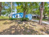 Charming single-story home with a vibrant blue exterior nestled among mature trees at 770 Arthurs Ct, Tarpon Springs, FL 34689