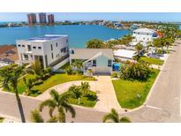 Stunning waterfront home featuring lush landscaping, a circular driveway, and picturesque views of the bay and cityscape at 118 Wall St, Redington Shores, FL 33708