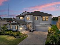 Two-story home with stone accents, a paver driveway, and a two-car garage near a lake at 12808 Boggy Creek Dr, Riverview, FL 33579