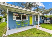 Charming blue home featuring a cozy front porch area with table, chairs, and vibrant hanging flower baskets at 133 15Th Nw St, Largo, FL 33770