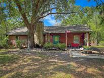 Charming log cabin with stone chimney, lush landscaping, and inviting front porch at 14114 N 301 Hwy, Thonotosassa, FL 33592
