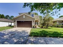 Charming two-story home with a well-manicured lawn, an attached two-car garage and neutral stucco exterior at 4250 Warwick Hills Dr, Wesley Chapel, FL 33543