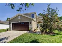 Charming two-story home with a well-maintained lawn, brown garage door, and inviting entryway, offering curb appeal at 4250 Warwick Hills Dr, Wesley Chapel, FL 33543
