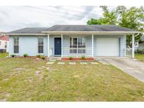 Charming single-story home with light blue paint, inviting front porch and well-manicured lawn and a single car garage at 7934 Aden Loop, New Port Richey, FL 34655