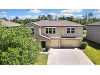 Two-story home featuring a three-car garage, neutral stucco exterior, and well-maintained landscaping at 35965 Saddle Palm Way, Zephyrhills, FL 33541