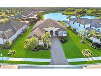 Stunning aerial view of home with lush lawn, mature trees, tile roof, and lake view at 4824 Benito Ct, Bradenton, FL 34211