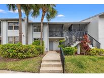 Charming condo featuring a landscaped yard, screened porch, and stairs to the entryway at 1998 Blue Hawk Ct # 1613, Clearwater, FL 33762