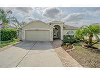 Charming single-story home featuring a well-manicured lawn, brick walkway, and attached two-car garage at 3138 Clover Blossom Cir, Land O Lakes, FL 34638