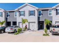 Well-maintained townhomes featuring attached garages, manicured landscaping, and neutral two-tone paint at 34355 Sorrel Mint Dr, Wesley Chapel, FL 33543