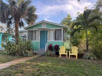 Charming home with a blue door, palm trees, and yellow Adirondack chairs, offering a cozy welcome at 5314 21St S Ave, Gulfport, FL 33707