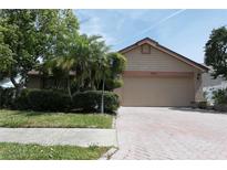 Charming single-story home featuring a brick driveway, mature landscaping, and an attached two-car garage at 8609 Thimbleberry Ln, Tampa, FL 33635
