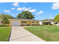 Charming yellow ranch-style home with a lush green lawn and a long driveway, perfect for suburban living at 145 Avon Dr, Safety Harbor, FL 34695