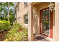 Charming front porch featuring a red door, sidelight and decorative flower wreath at 4206 Preserve Pl, Palm Harbor, FL 34685