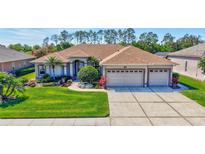 Charming home featuring a well-manicured lawn, lush landscaping, and a three-car garage at 5137 Epping Ln, Zephyrhills, FL 33541