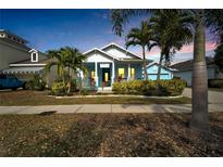 Charming blue single-story home featuring a welcoming front porch and lush tropical landscaping at 527 Manns Harbor Dr, Apollo Beach, FL 33572