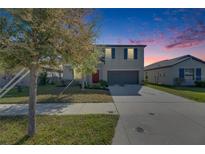 Charming two-story home with a well-maintained lawn and driveway at dusk at 11828 Miracle Mile Dr, Riverview, FL 33578