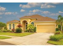 Stunning yellow home with a manicured lawn, beautiful landscaping, and a two-car garage at 2218 132Nd E Pl, Parrish, FL 34219