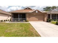 Charming one-story home boasts a well-manicured lawn, a screened-in porch, and a two-car garage at 5664 Legend Hills Ln, Spring Hill, FL 34609