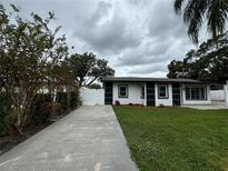 Inviting single-story home featuring a well-manicured lawn and modern black-and-white exterior at 7608 Lakeside Blvd, Tampa, FL 33614