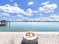 Beautiful water view with a fire pit in the foreground and a dock on the left side of the frame at 882 Bay Point Dr, Madeira Beach, FL 33708