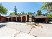 View of garage with arched entries and water fountain in circular driveway at 8820 S Hickory Ln, Riverview, FL 33578