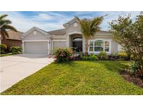Charming single-story home featuring a well-manicured lawn, mature landscaping, and a two-car garage at 11335 77Th E St, Parrish, FL 34219