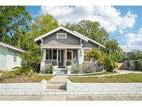 Charming gray home showcasing lush landscaping, manicured lawn, and a welcoming front entryway at 114 E Emily St, Tampa, FL 33603