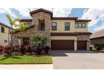 Beautiful two-story home featuring stone accents, a three-car garage, and a well-manicured lawn with palm trees at 11966 Climbing Fern Ave, Riverview, FL 33579
