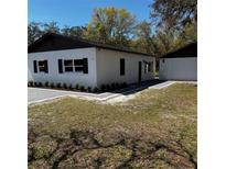 A charming single-story home featuring a well-manicured lawn and a detached garage at 12903 Post Rd, Hudson, FL 34669